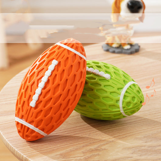 Orange rubber rugby ball dog toy with honeycomb texture and white laces, being squeezed by a hand. - Image 7