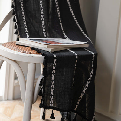 Black polyester curtain with white jacquard multi-line pattern and black tassels, draped over a white chair. - Image 13