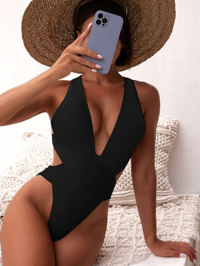 Woman in a black one-piece swimsuit with a deep V-neck and criss-cross waist cutouts, wearing a straw hat. - Image 14