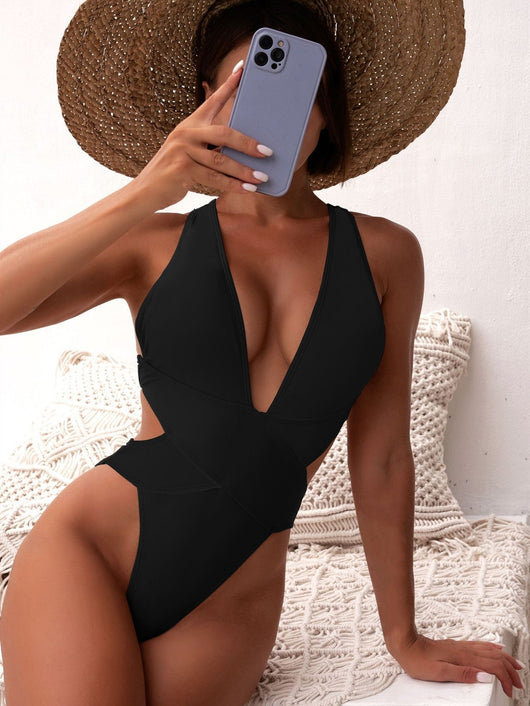 Woman in a black one-piece swimsuit with a deep V-neck and criss-cross waist cutouts, wearing a straw hat. - Image 14