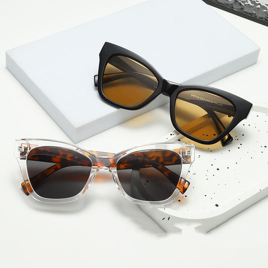 Fashion sunglasses with clear oval frames, dark gray lenses, and tortoise shell patterned temples.