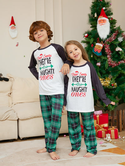 Man wearing a white and black raglan long-sleeve pajama top with a 'Dear Santa They're the Naughty Ones' graphic and green plaid pajama pants. - Image 2