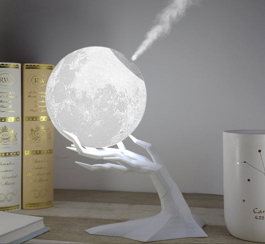 Moon-shaped humidifier and night light with a white deer stand, emitting mist, on a wooden table with books. - Image 6