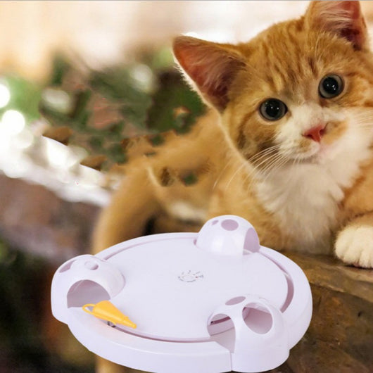 White interactive cat toy with a yellow feather, designed for mouse pouncing, next to a silver tabby cat. - Image 2