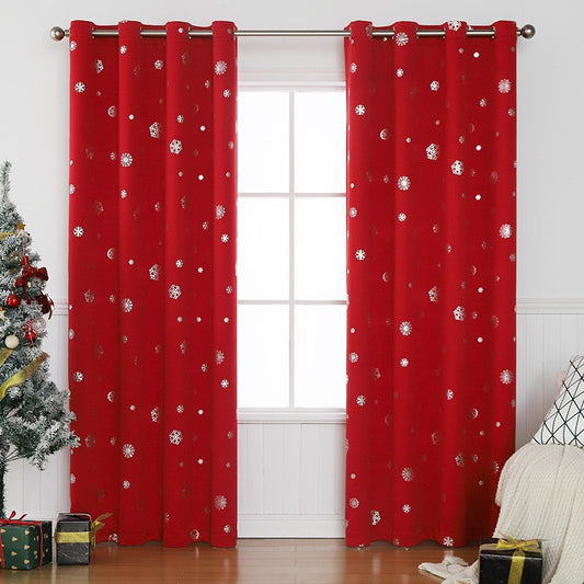 Dark green blackout curtains with silver snowflake patterns, hung on a rod in a room with a Christmas tree.
