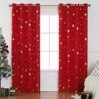 Dark green blackout curtains with silver snowflake patterns, hung on a rod in a room with a Christmas tree.