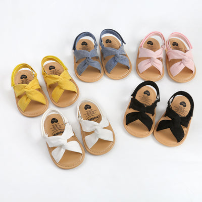 Black baby sandals with knotted cross straps and a matching black floral headband on a white background. - Image 3