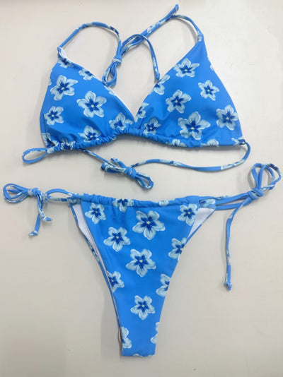 Blue floral print string bikini with triangle top and tie-side bottoms on a model in shallow ocean water. - Image 15
