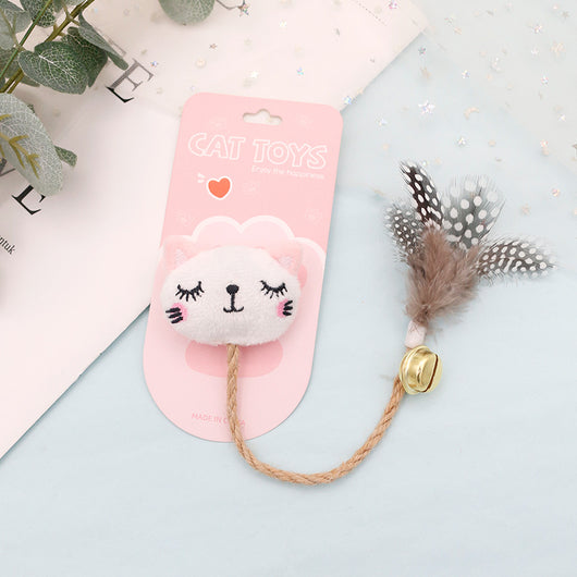 White cat head plush teaser toy with hemp rope, gold bell, and natural spotted feathers on pink packaging. - Image 4