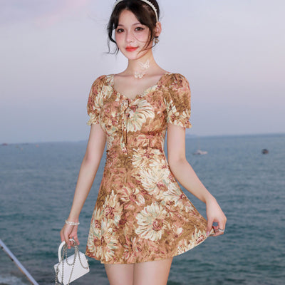 Woman in a blue and pink floral print swimsuit with puff sleeves and a square neckline, standing by the ocean. - Image 9