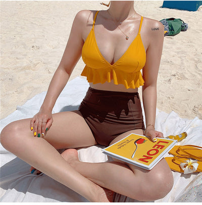 Woman in a yellow ruffled bikini top and dark brown high-waisted bottoms sitting on a beach. - Image 16