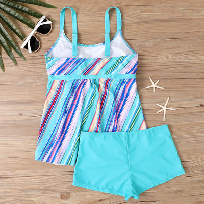 Woman in a black and white abstract print tankini top with black swim shorts on a sunny beach. - Image 18