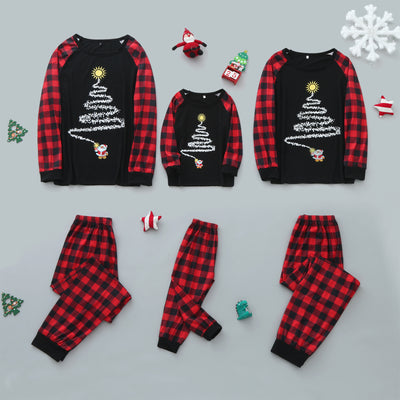Family of five wearing matching black and red buffalo plaid Christmas pajamas with a white Christmas tree print.