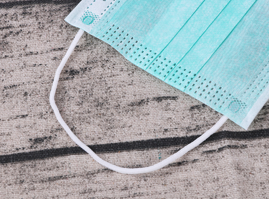 Stack of pink disposable non-woven face masks, with one unfolded and one folded, on a light wood surface. - Image 7