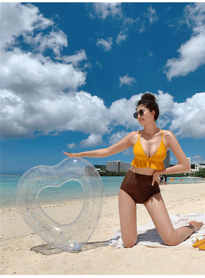 Woman in a yellow ruffled bikini top and dark brown high-waisted bottoms sitting on a beach. - Image 9