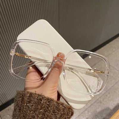 Black oversized square anti-blue light glasses with clear resin lenses and gold metal frame details, held by a hand. - Image 7
