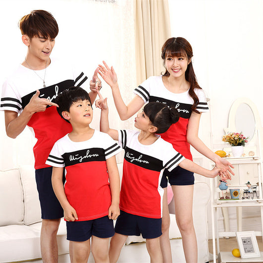 Family of four wearing matching black, white, and red color block t-shirts with navy shorts, posing happily. - Image 14