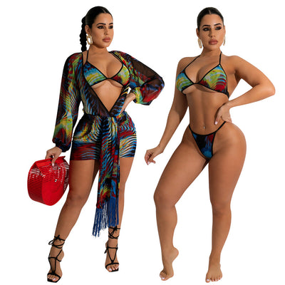 Model wearing a blue, red, and yellow abstract print three-piece mesh swimsuit set with a bikini top, mini skirt, and long-sleeve cover-up. - Image 5