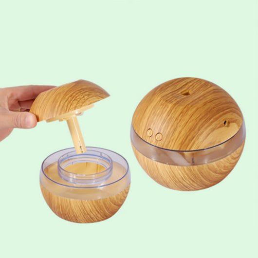Spherical wood grain humidifier with a clear band, emitting mist, against a dark background with lotus flowers. - Image 10