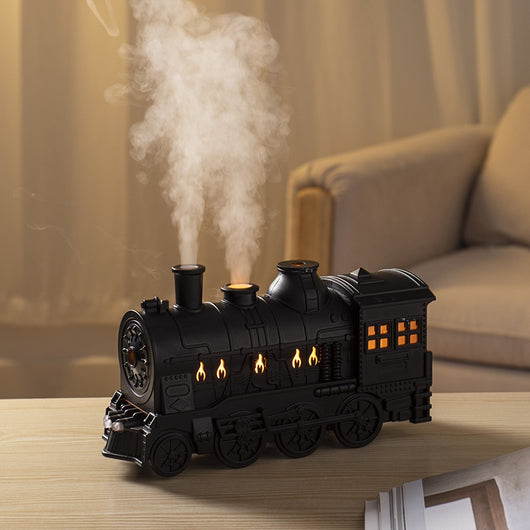 Black train-shaped essential oil diffuser and humidifier with retro design, emitting mist and glowing lights.