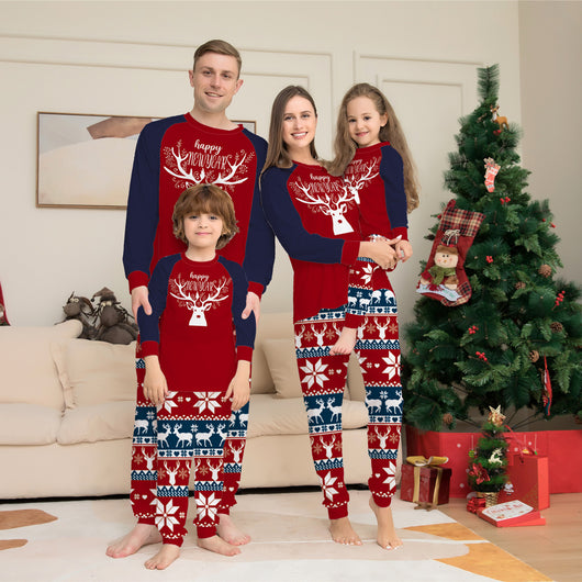 Child wearing a red and navy blue Christmas pajama set with a white reindeer and "happy NEW YEAR" text on the top, and fair isle pattern pants.