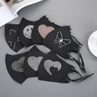 Black ear-mounted mask with a sparkling rhinestone bow pattern, featuring adjustable ear loops.