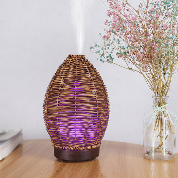 Hollow rattan aroma diffuser with an egg-shaped woven brown exterior and a light wood-grain base.