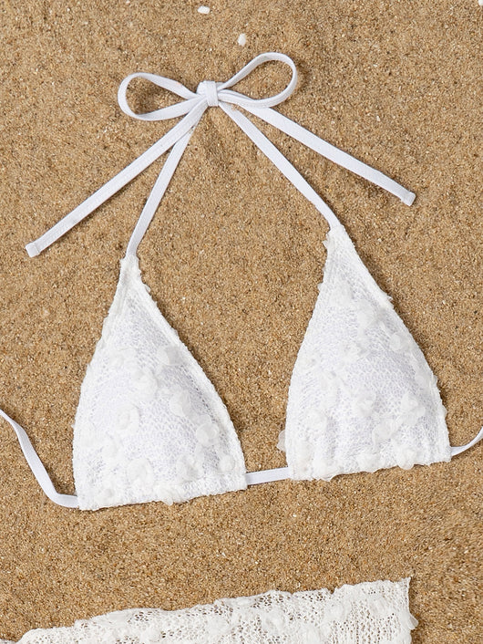 White lace halter bikini set with a matching mesh sarong, laid out on sand with sunglasses and a palm leaf. - Image 24