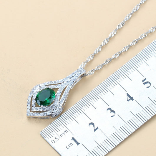 Silver-toned three-piece jewelry set with clear oval and round gems, including a necklace, dangle earrings, and a ring. - Image 5
