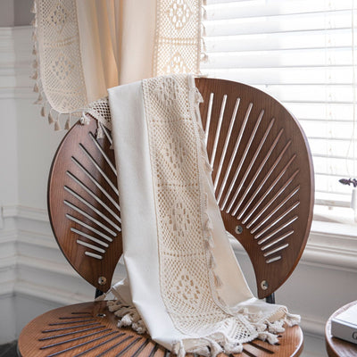 Close-up of a beige semi-transparent curtain with a delicate crochet lace trim and decorative tassels. - Image 10