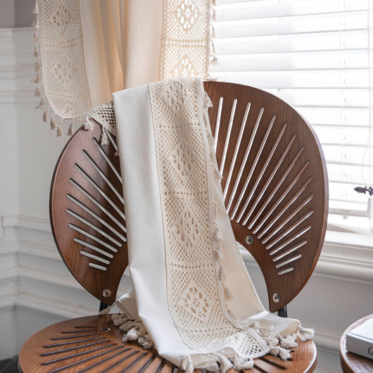 Close-up of a beige semi-transparent curtain with a delicate crochet lace trim and decorative tassels. - Image 10