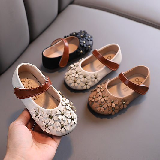 Black Mary Jane shoes for girls with 3D flower appliques on the toe and a brown hook-and-loop strap.