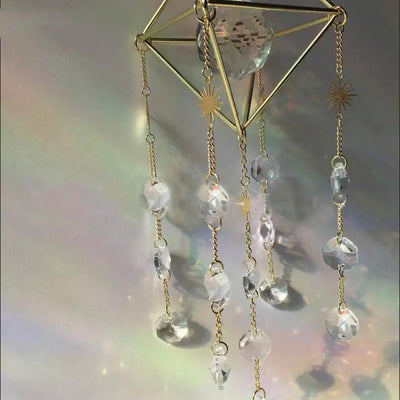 Geometric iridescent suncatcher with a gold frame and dangling crystal pendants, held in a hand, creating rainbow light. - Image 15
