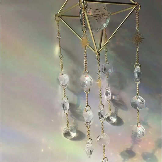 Geometric iridescent suncatcher with a gold frame and dangling crystal pendants, held in a hand, creating rainbow light. - Image 15