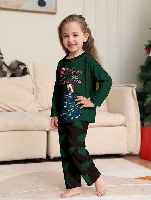 Young girl wearing a dark green long-sleeved Christmas pajama set with a decorated tree and "Merry Christmas" text. - Image 3
