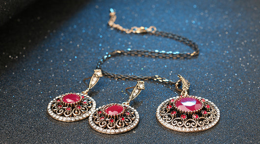 Vintage-style jewelry set with a necklace and matching drop earrings. Features red and clear gemstones in an antique gold-tone filigree design. - Image 9