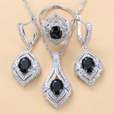 Silver-toned three-piece jewelry set with clear oval and round gems, including a necklace, dangle earrings, and a ring. - Image 2