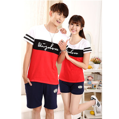 Family of four wearing matching black, white, and red color block t-shirts with navy shorts, posing happily.