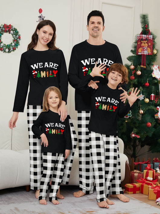 Family of four wearing matching black long-sleeve pajamas with "WE ARE FAMILY" text and black and white plaid bottoms. - Image 5