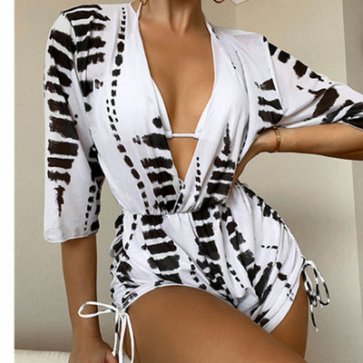 Woman wearing a white and black tie-dye beach cover-up romper with a deep V-neck and drawstring sides. - Image 4