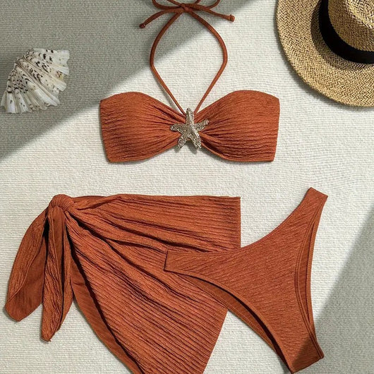 Rust three-piece swimsuit with textured fabric, featuring a tube top with a starfish, high-cut bottoms, and a sarong.