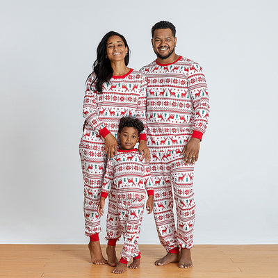 Family wearing matching white and red Christmas pajamas with elk and snowflake patterns, including a baby and a dog. - Image 3