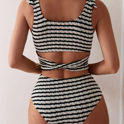 Women's black and white striped two-piece swimsuit with a tube top and high-waisted bottoms, worn by a person lounging on a white bed. - Image 4