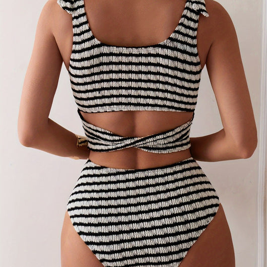 Women's black and white striped two-piece swimsuit with a tube top and high-waisted bottoms, worn by a person lounging on a white bed. - Image 4