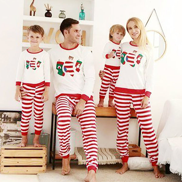 Father and son wearing matching Christmas pajamas with white long-sleeved tops featuring stocking prints and red and white striped pants.