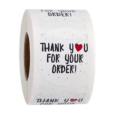 Roll of white round thank you stickers with black text, a red heart, and gold dots for orders.