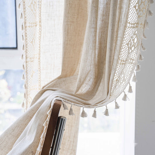 Close-up of a beige semi-transparent curtain with a delicate crochet lace trim and decorative tassels. - Image 13
