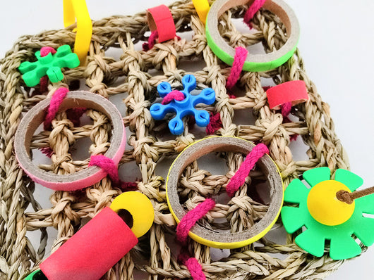 Colorful parrot bite toy with a woven grass mat, yellow plastic hangers, and various red, green, blue, and brown chewable components. - Image 4