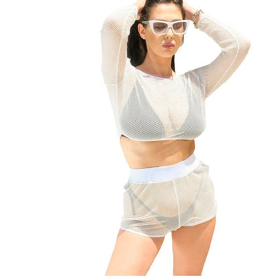 Woman in a white mesh long-sleeve crop top and matching shorts over a dark bikini, posing outdoors. - Image 5