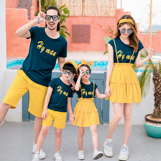 Family of four in matching dark blue short-sleeved tops with yellow text and yellow bottoms, posing outdoors. - Image 2